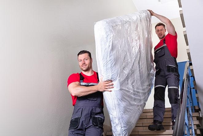 a worn-out box spring being lifted off a bed frame in Lansdowne